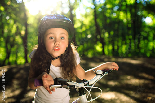 little girl with bicycle in summer park outdoors