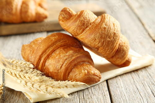Fotografie, Tablou Tasty croissants with spikelets on grey wooden background