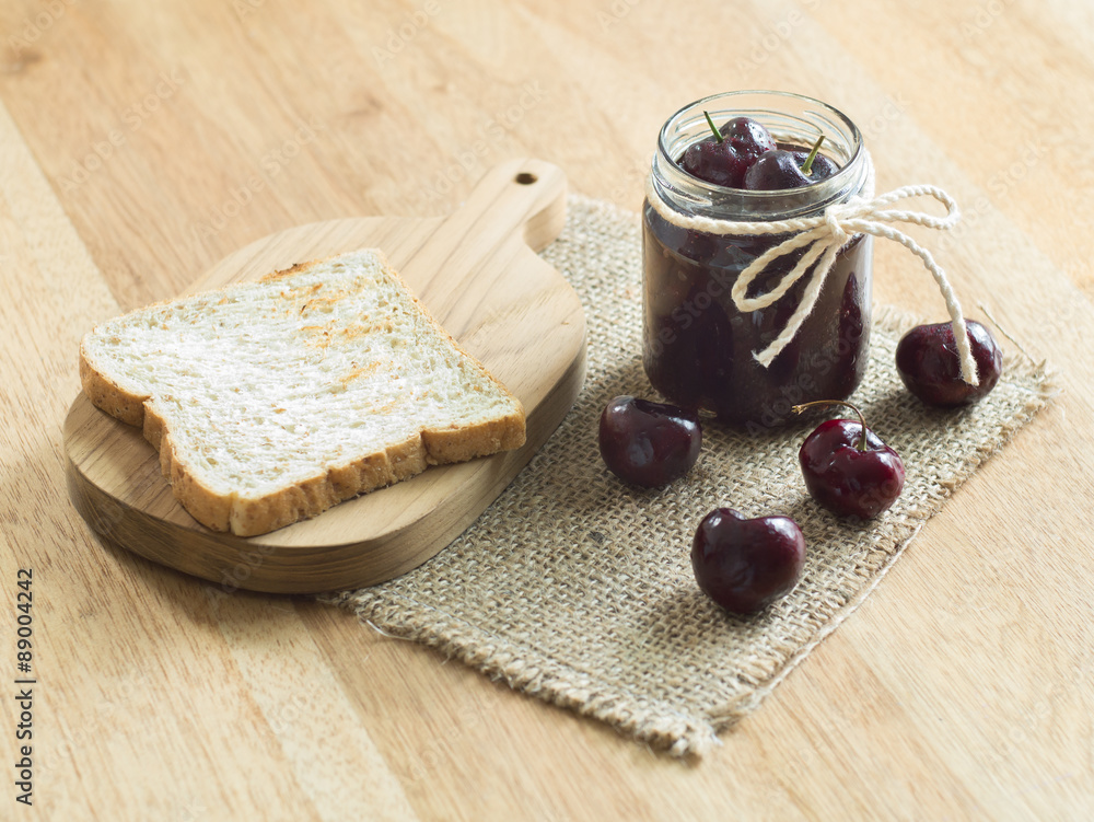 Cherry jam and toast on wooden background