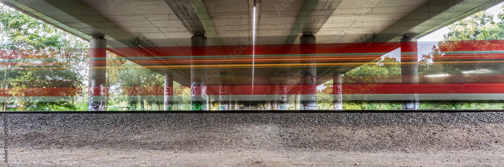 Fototapeta premium schneller Zug unter Autobahnbrücke