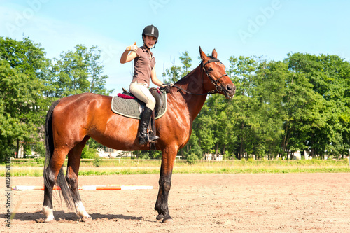 Teenage girl equestrian showing ok sign. Vibrant summertime outd