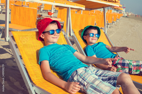 Little boys showing away in deckchair on beach
