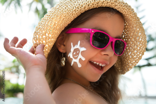 Happy child in glasses with sunscreen on the face