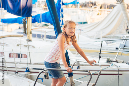 Cute little girl resting on a yacht in a port on a nice summer day