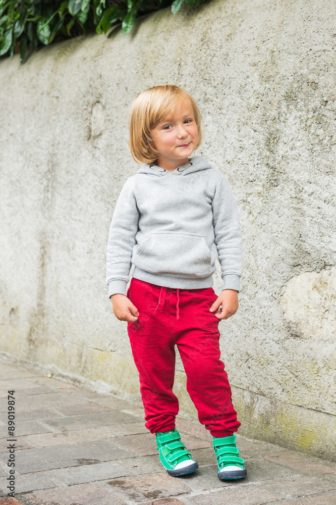 Fashion portrait of adorable toddler boy wearing grey sweatshirt, red trainings and green shoes Fashion portrait of adorable toddler boy wearing grey sweatshirt, red trainings and green shoes