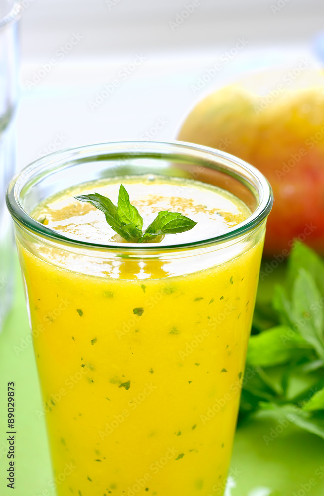 Cooling Mango mint smoothie, summer drink on green table, Yellow Tropical Smoothie made with mango, mint and lime juice. Copy space. Cooling Mango mint smoothie, summer drink on green table, Yellow Tropical Smoothie made with mango, mint and lime juice. Copy space.