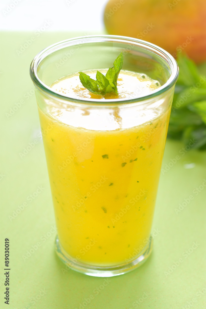 Cooling Mango mint smoothie, summer drink on green table, Yellow Tropical Smoothie made with mango, mint and lime juice. Cooling Mango mint smoothie, summer drink on green table, Yellow Tropical Smoothie made with mango, mint and lime juice.