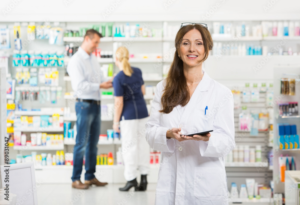 Smiling Female Chemist Holding Digital Tablet At Pharmacy