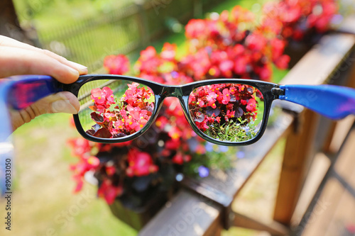 optical eyeglasses in the hand over blurred flower background