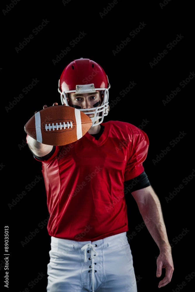 Portrait of american football player showing football to camera