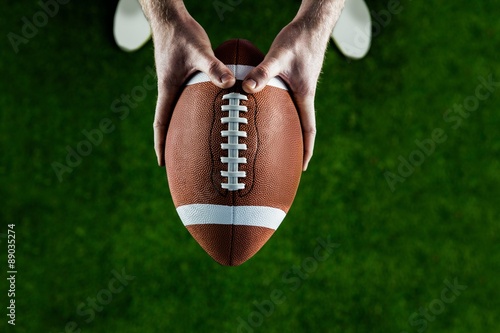 American football player holding up football photo