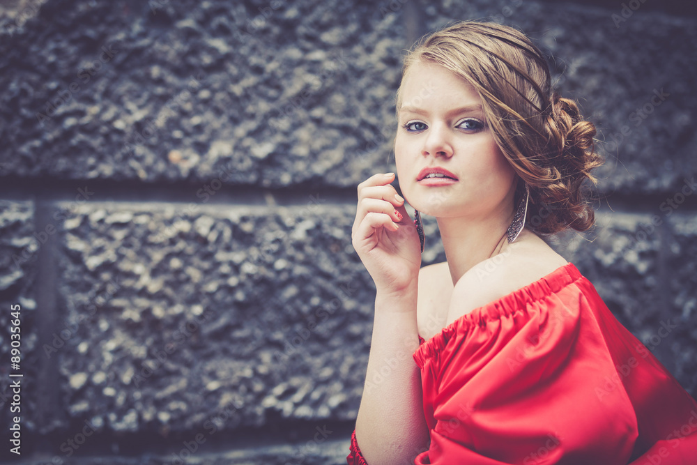 Fototapeta premium portrait of a beautiful young girl in a red dress outdoors