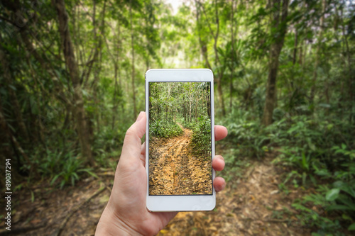 Business conceptual- Focused on left hand holding mobile with Trekking nature blurred background