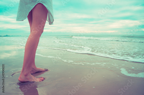 Female leg walking on the beach in the ocean.Vintage filter.