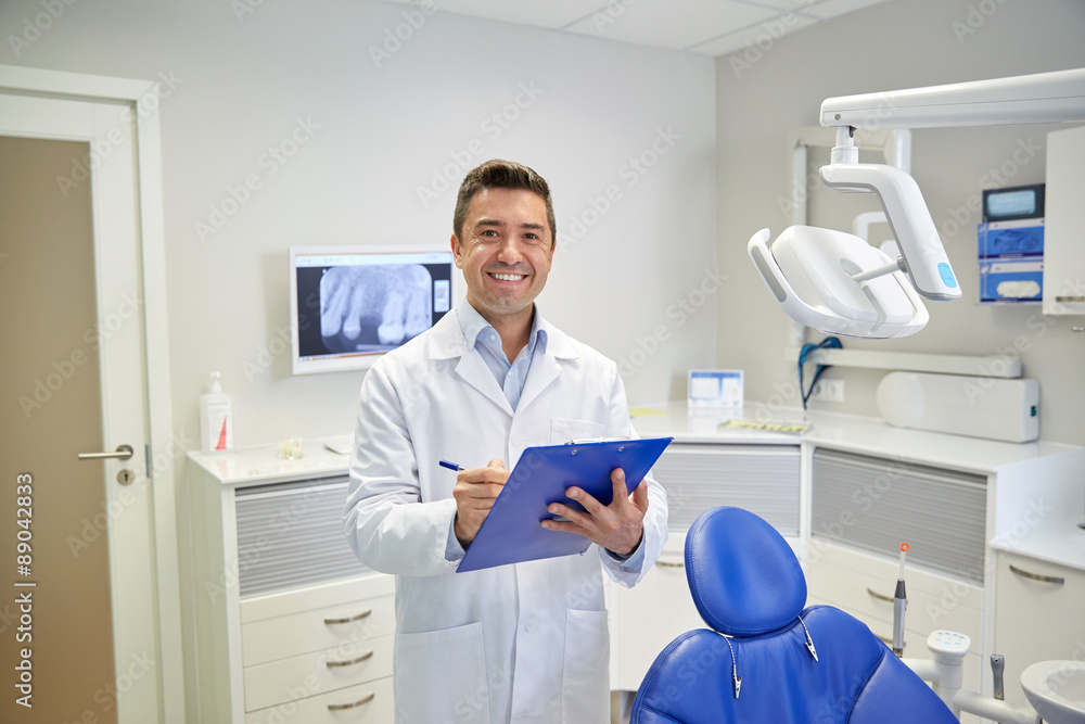happy male dentist with clipboard at dental clinic happy male dentist with clipboard at dental clinic