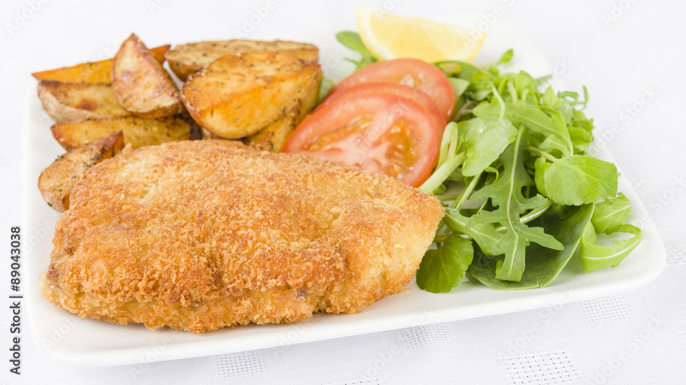 Wiener Schnitzel - Veal steak breaded and fried in butter served with salad, potato wedges and a lemon slice. Wiener Schnitzel - Veal steak breaded and fried in butter served with salad, potato wedges and a lemon slice.