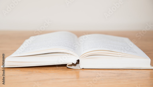 White open book on wooden table with soft focus