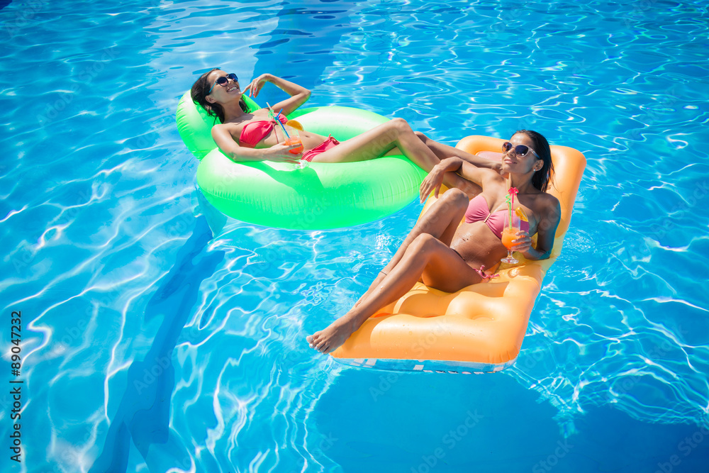 Girls resting on air mattress in swimming pool