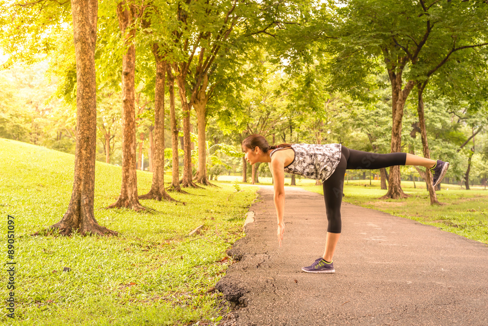 Fototapeta premium Side view of woman runner stretching warm up with single-leg dea