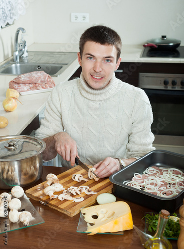  man cooking meat with  mushrooms and potatoes - cutting mushroo photo