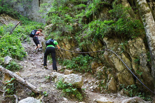 Hikers on a perilous trail, holding the safety line