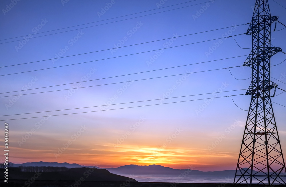 Электро башня на фоне восхода солнца над морем
