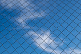 iron fence on a blue sky with small clouds
