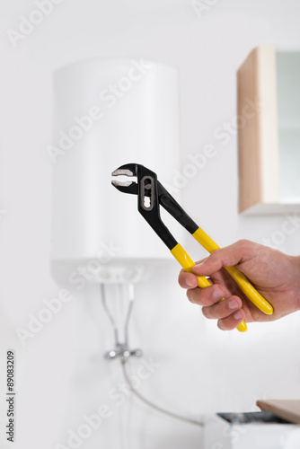 Person Hands With Wrench In Front Of Electric Boiler