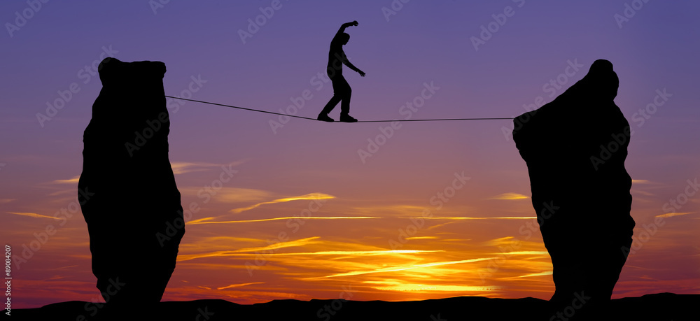 Silhouette of a man walking on the tightrope Stock Photo