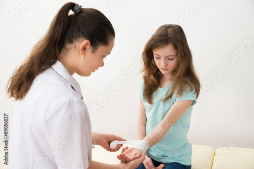 Doctor Bandaging Hands Of Girl Child