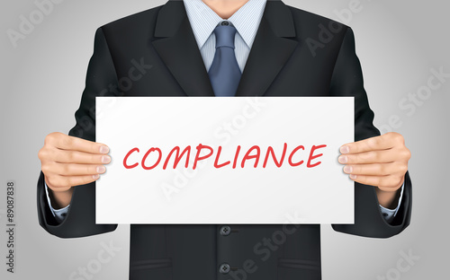 businessman holding compliance word poster