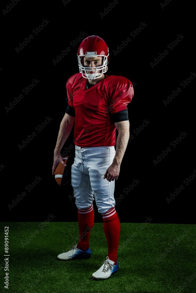 Portrait of american football player holding football