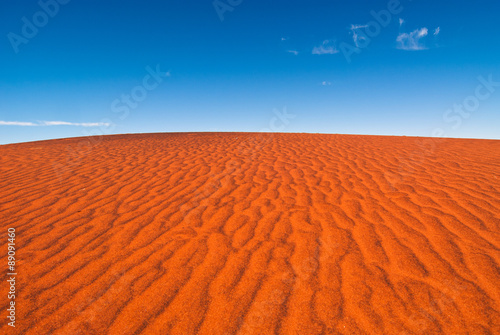 A rippled red sand dune against a clear blue sky, taken near Uluru in central Australia