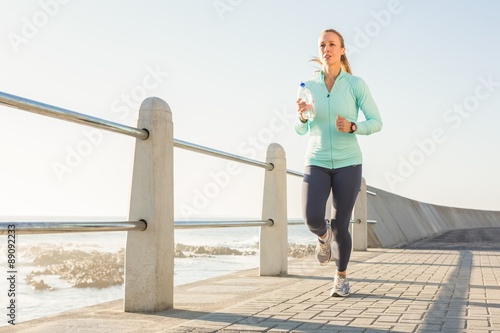 Fototapet Focused fit blonde jogging at promenade