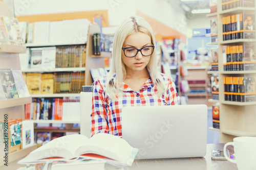 Portrait of a young student using her laptop in a library
