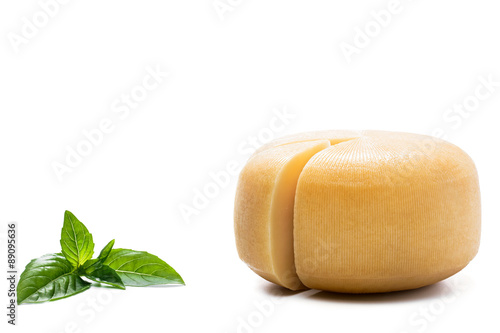 Yellow round cheese and basil leaves on white background