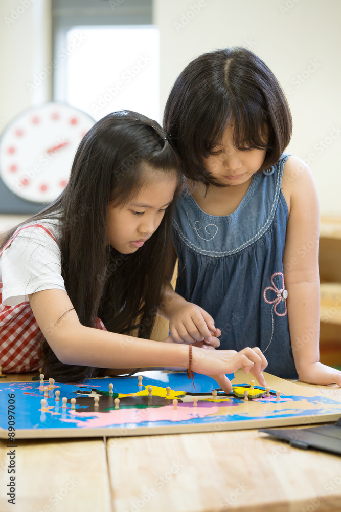 Fototapeta premium Little asian girl looking South america asia for play jigsaw