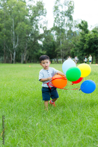 Little boy walking with bruch of balloon