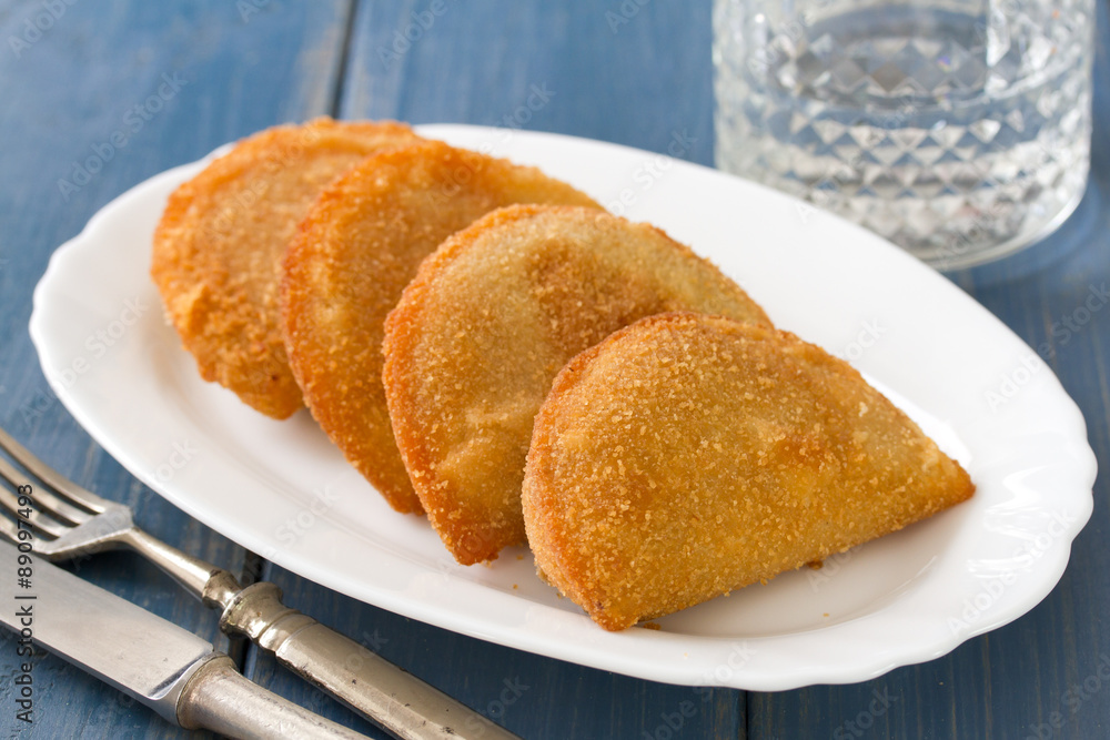 portuguese meat cookies, rissois on white dish on blue background portuguese meat cookies, rissois on white dish on blue background