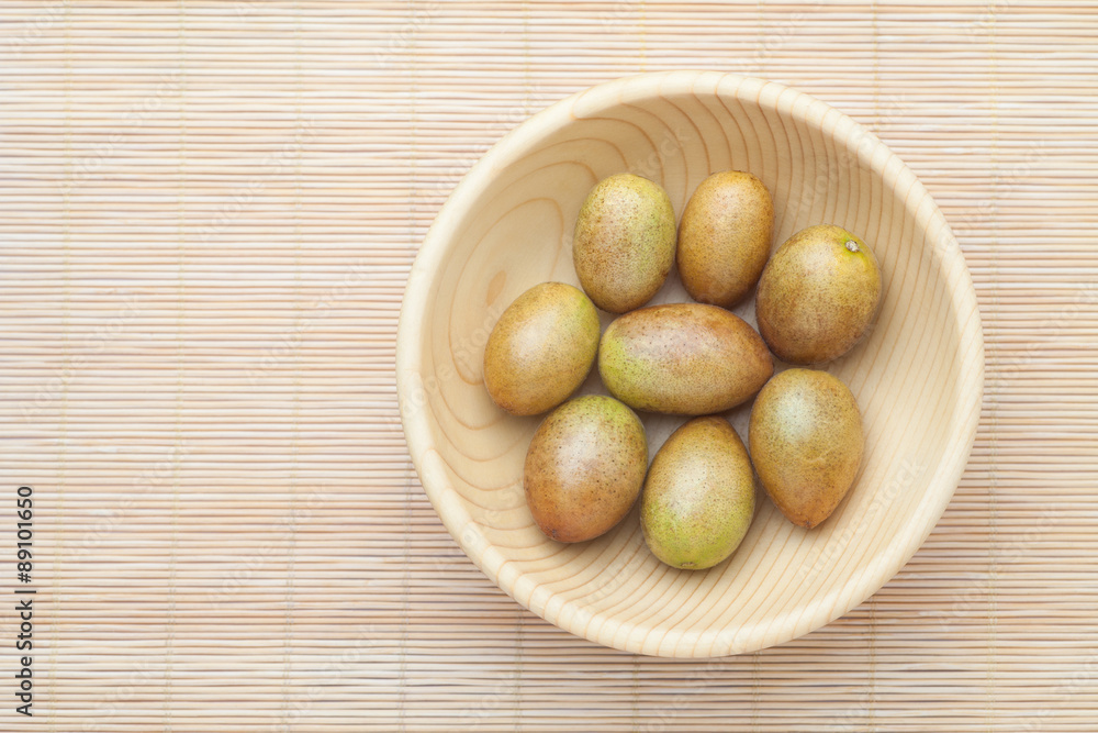 Fresh wampee fruit in wooden bowl. Wampee fruit is a tropical fruit native to southern China. Fresh wampee fruit in wooden bowl. Wampee fruit is a tropical fruit native to southern China.