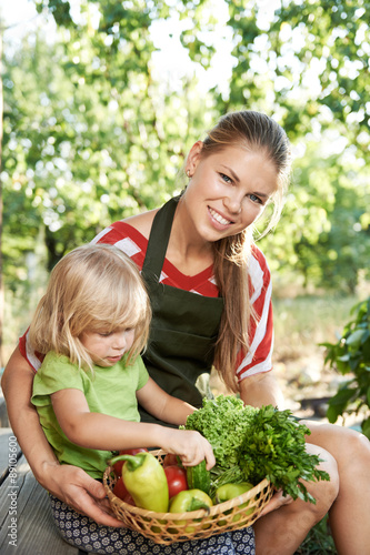 Family weekend activity. Young mother with child holding vegetables