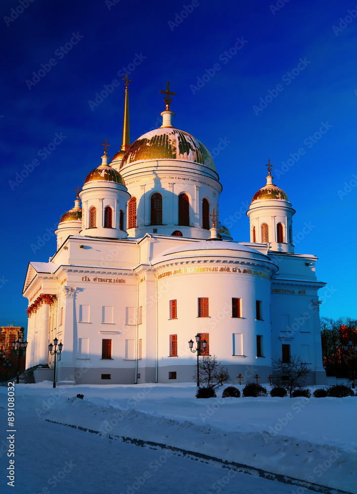 White orthodox church with gold domes against  blue winter sky