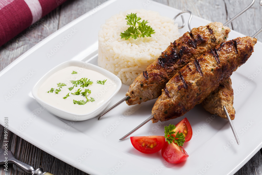 Barbecued kofta - kebeb with rice and vegetables on a plate.