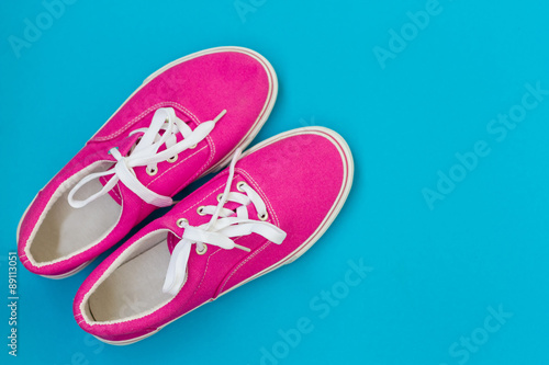 Pink sneakers with laces on a blue