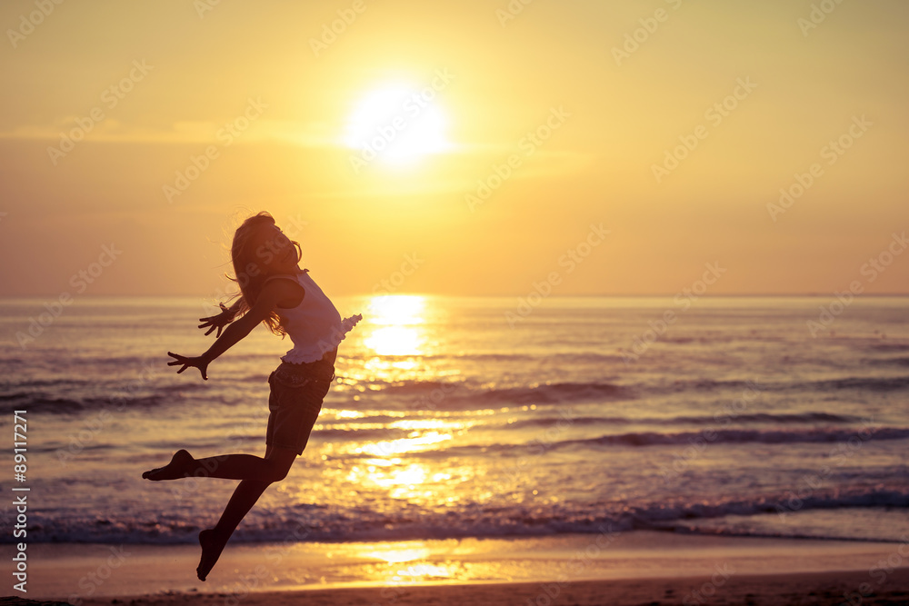 Happy little girl jumping on the beach