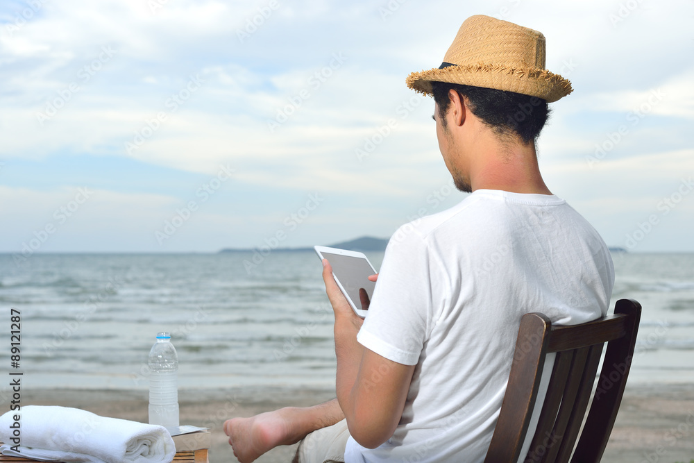 Man relaxing and use tablet computer at beautiful tropical beach