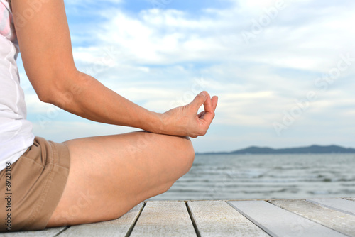 Woman practicing yoga meditation on the beach