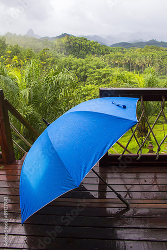 blue umbrella on a wooden deck with mountain view © vichly4thai