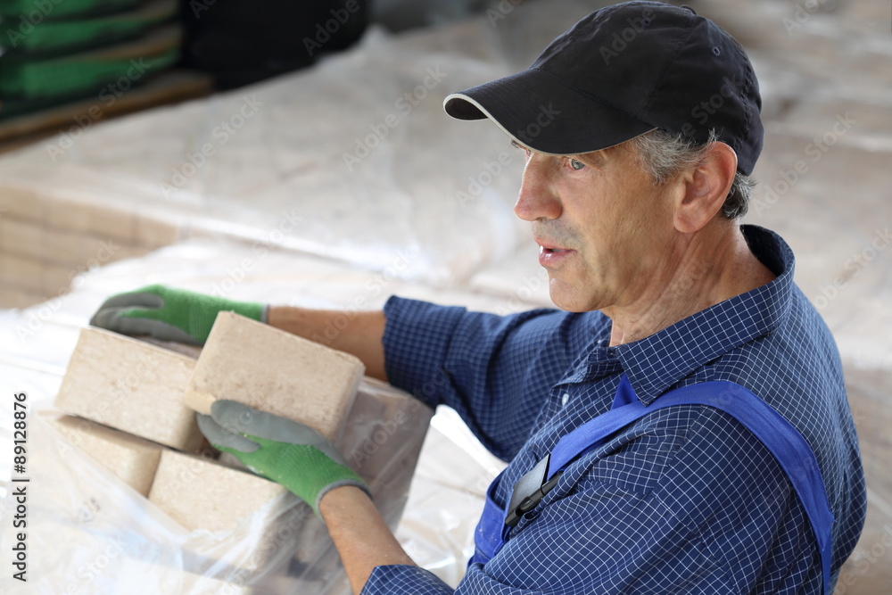 Mann mit Paletten von Holzbriketts Mann mit Paletten von Holzbriketts