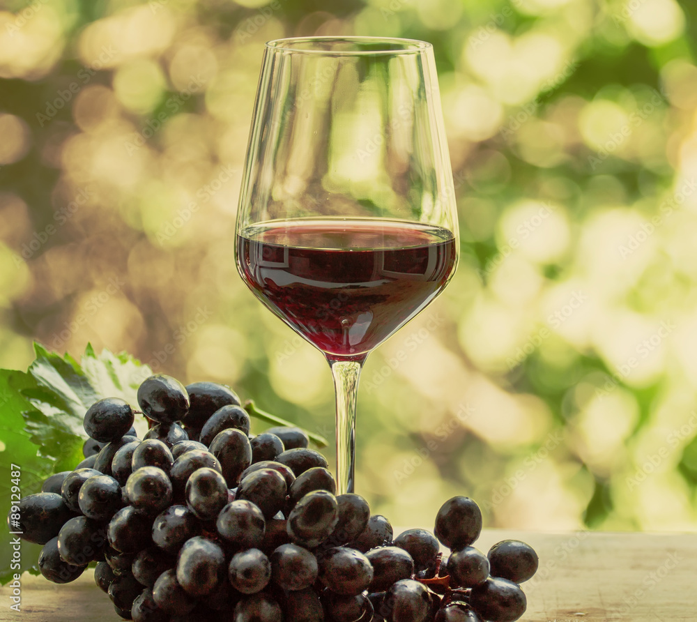Red wine in a glass and fresh grapes, toned image, selective foc